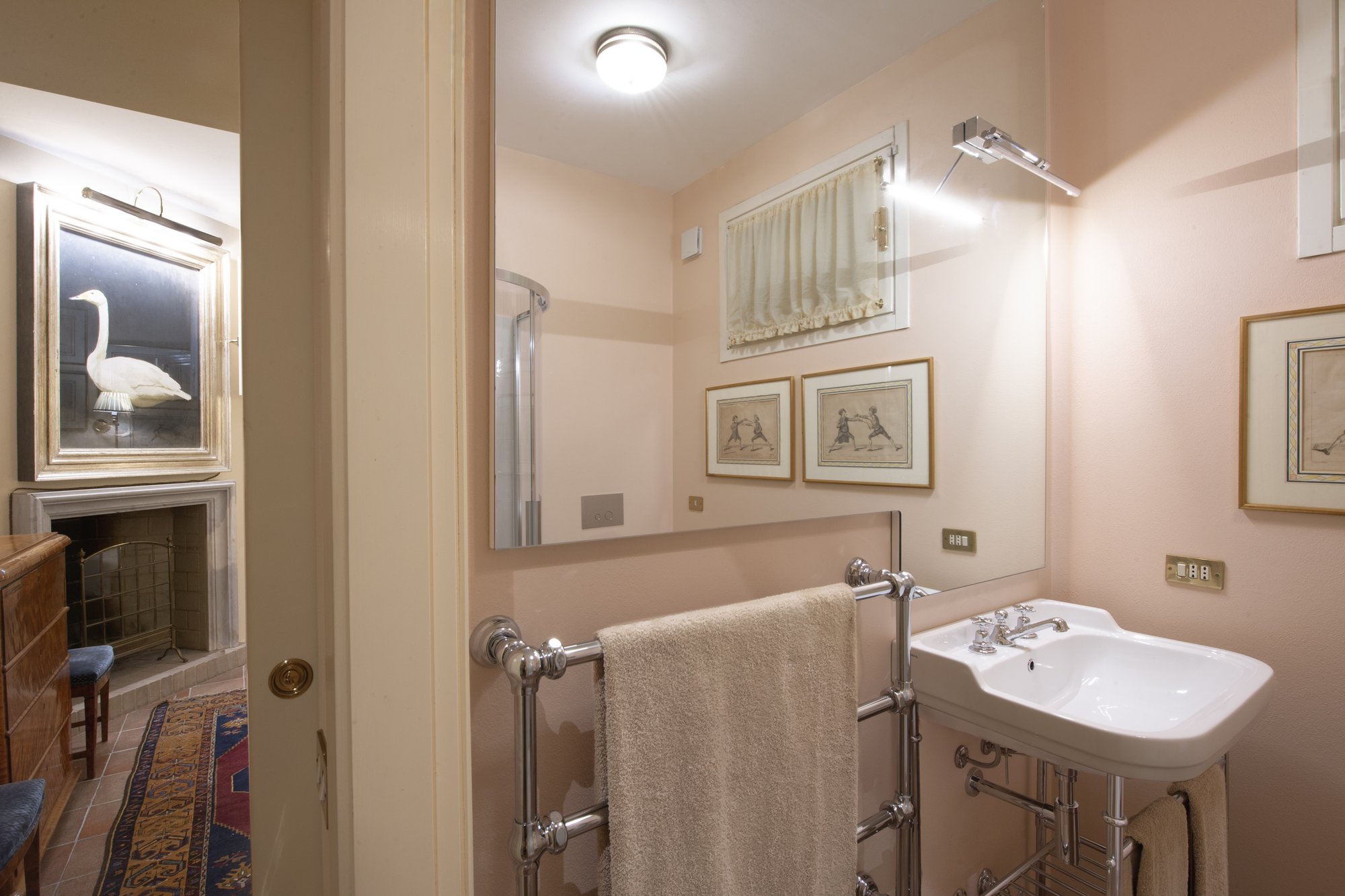 Pink bathroom with chrome washstand, fencing prints and a swan painting