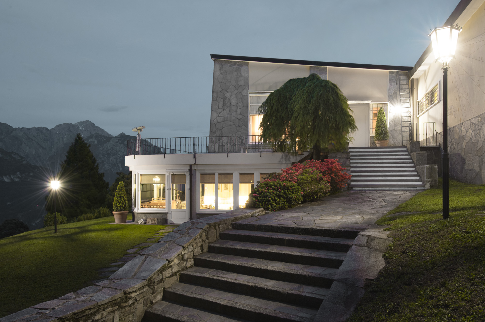 The main villa illuminated at night, with lanterns along the stone steps